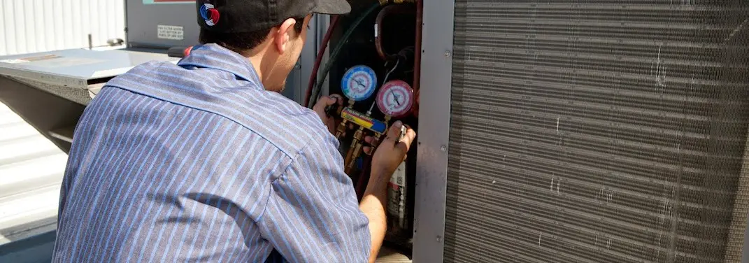 HVAC technician servicing a condenser unit in Swissvale